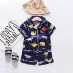 The Midnight Dino PJ Set - A smooth navy blue satin pajama set with a colorful, all-over cartoon dinosaur print